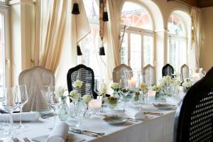 林道维里诺酒店的用餐室配有带玻璃杯和鲜花的长桌