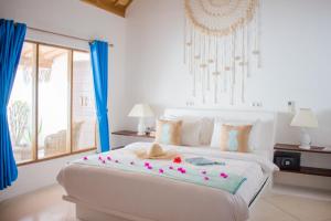 吉利阿尔日出度假村的一间卧室配有一张白色大床,床上有鲜花