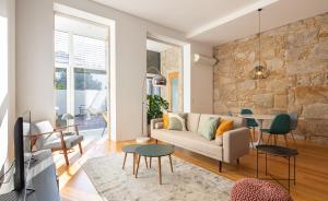 波尔图Trindade Premium Suites & Apartments的带沙发和石墙的客厅