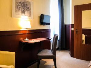 吕贝克汉萨酒店的客房设有一张桌子、一把椅子和一台电视