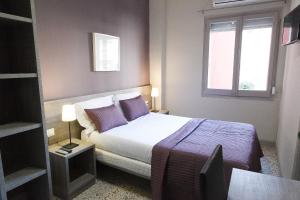 坎布里尔斯Hostal Fonda Montserrat的一间卧室配有一张带紫色枕头的床和窗户。