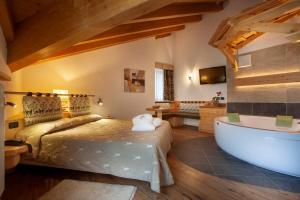 莫埃纳Resort Dolce Casa - Family & Spa Hotel的一间卧室设有一张大床和一个浴缸