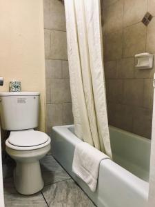 特克萨卡纳特克萨卡纳行政汽车旅馆的浴室设有卫生间、浴缸和淋浴帘。