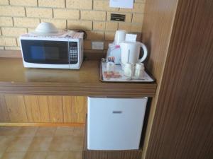 布里斯班艾斯普利先锋汽车旅馆的厨房柜台配有微波炉和小冰箱