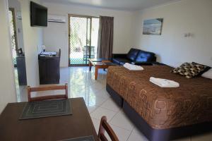 马库拉太平洋棕榈莫泰饭店的一间卧室配有一张床、一张桌子和一张沙发