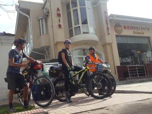 撒马尔罕阿米尔旅舍的三个人站在一幢楼前,骑着自行车