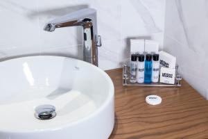伊斯坦布尔Meydan Besiktas Hotel的白色浴室水槽,配有水龙头和一些化妆品