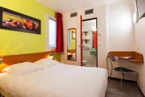 勒河畔的圣马丁ENZO HOTELS Chalons en Champagne的一间带白色床和书桌的卧室以及一间浴室。