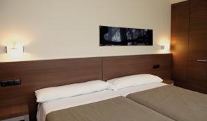 阿尔特萨苏艾泽雷酒店的一间卧室设有两张床,墙上配有电视。