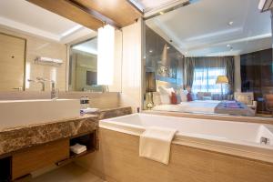 曼谷Graceland Bangkok by Grace Hotel - SHA Extra Plus的一间带大浴缸和大镜子的浴室