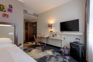 慕尼黑慕尼黑奥林匹克公园美居酒店的酒店客房配有一张床和一张书桌及一台电视