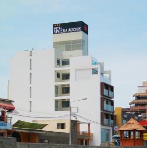 万查科Hotel Riviera Muchik的一座高大的白色建筑,上面有标志