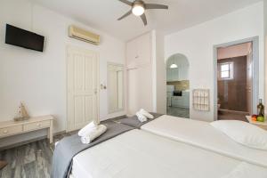 德里奥斯塔萨公寓酒店的白色卧室配有一张带吊扇的大床