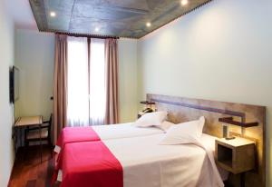 韦斯卡Hospedium Hotel Posada De La Luna的一间卧室配有一张大床,铺有红白毯子