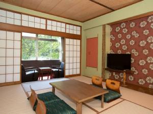 郡山Itoen Hotel Bandai Mukaitaki的配有桌椅和电视的客房
