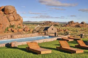 KanebisGondwana Canyon Village的沙漠中的一座带椅子的游泳池和一座建筑