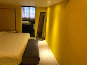 仙本那The Wharf的一间卧室设有一张床和黄色的墙壁