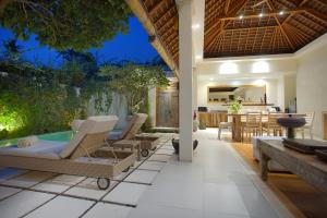 塞米亚克巴厘阿斯里巴图贝里别墅酒店的户外庭院设有热水浴池和桌椅。