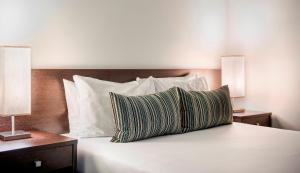 阿德莱德Franklin Apartments的一张带白色枕头的床和两张带灯的床头柜
