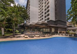 宿务Seda Ayala Center Cebu的一座带躺椅的游泳池和一座建筑