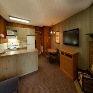 班夫花旗松小屋度假酒店的厨房配有柜台、桌子和电视。