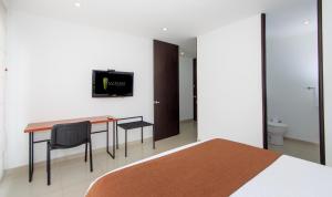 波哥大122广场公寓式酒店的一间卧室配有一张桌子和一台墙上的电视。