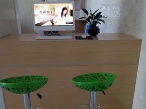 银川格林联盟宁医大附院银川汽车南站酒店的一张带两个绿色凳子的桌子和一台电视机