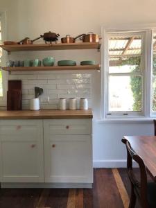 德韦灵阿普Gallery House Dwellingup的厨房配有白色橱柜、桌子和窗户。