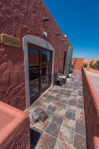 吕德里茨Island Cottage Guesthouse的沙漠中一座红色的建筑,有一条铺瓷砖的走道