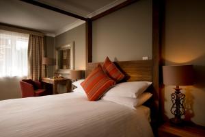 奇切斯特Crouchers Hotel的一间卧室配有一张带橙色和白色枕头的大床