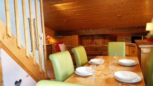 莱德萨阿尔卑斯娄维诺公寓的一间带木桌和绿色椅子的用餐室