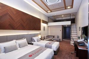 平昌Pyeongchang Ramada Hotel & Suite by Wyndham的酒店客房配有两张床和一张书桌