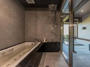 日田市乌梅奥下塔温泉旅馆的大型浴室设有浴缸和淋浴。