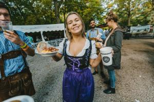 慕尼黑Oktoberfest and Springfest Inclusive Camping的拿着一盘食物和一杯杯子的女人