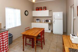 奥茨胡恩Hazenjacht Karoo Lifestyle - Oom Manus se Huis的厨房配有木桌和冰箱。