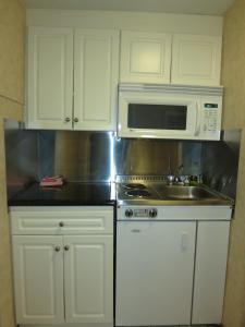 北温哥华北温哥华酒店的厨房配有白色橱柜、水槽和微波炉