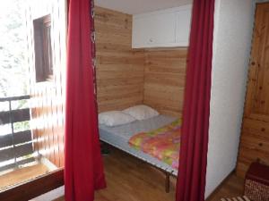 马尼戈La Combe Blanche 1307的一张小床,房间设有红色窗帘