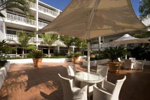 凯恩斯Ramada By Wyndham Cairns City Centre的庭院配有桌椅和遮阳伞。