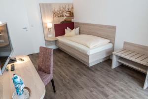 诺尔登堤岸布赫霍尔茨弗罗曼斯乡村酒店的小房间设有一张床和一张桌子