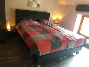雷杜Lesse matinal的卧室内的一张床位,配有红色和灰色的被子
