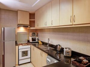 迪拜迪拜兹切公寓式酒店的厨房配有木制橱柜、水槽和冰箱。