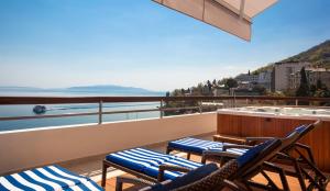 奥帕提亚Hotel Admiral - Liburnia的阳台配有椅子和热水浴池,享有水景。