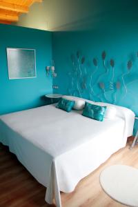 Las Rozas de Valdearroyo阿拉兹酒店的一间卧室配有一张白色大床和蓝色的墙壁