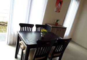 巴图Villa Sakura Kusuma Estate的餐桌、四把椅子和一张鲜花桌子