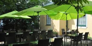 珀希拉恩莫泽餐厅酒店的一组桌椅,配有绿色遮阳伞