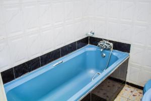 卢萨卡Rugems Executive Lodge的浴室铺有白色瓷砖,配有蓝色浴缸。