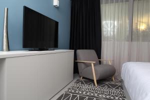 伦达瓦Hotel Cubis的配有电视、椅子和床的房间