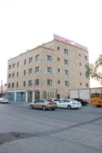 尼兹瓦MY HOTEL Nizwa Residence Hotel Apartement نزوى ريزيدنس的一座大型砖砌建筑,停车场内有车辆停放