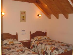 VidángozCasa rural Ornat Etxea的卧室设有2张床和木制天花板。