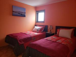 纳塔列斯港Hostal Nataly的红色的客房设有两张床和窗户。